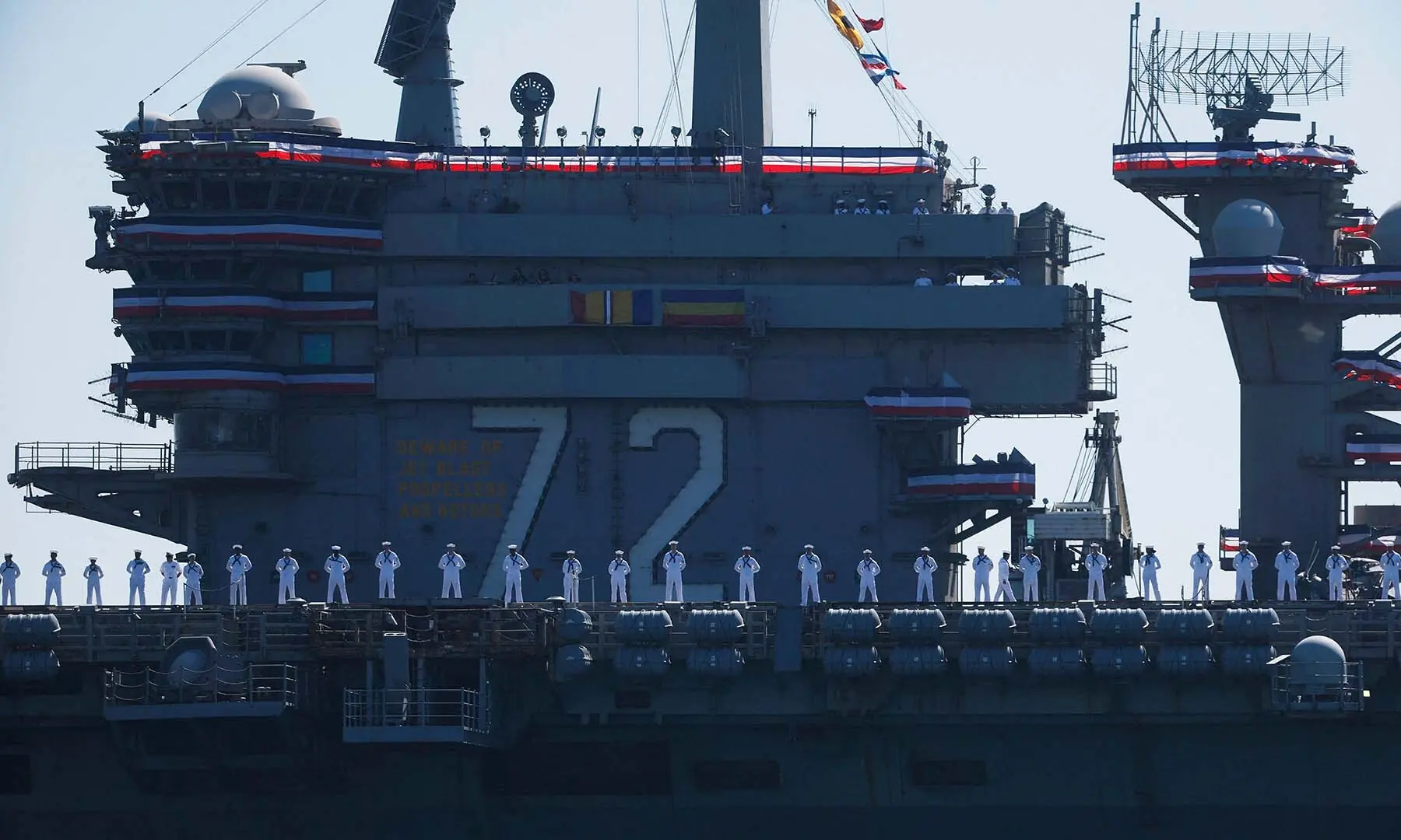 Crew members stand on the deck as the USS Abraham Lincoln aircraft carrier approaches its homeport at Naval Air Station North Island on return from its historic 10-month deployment to the Middle East on October 8, 2026 as seen from the Port of San Diego in San Diego, California. &mdash; AFP
