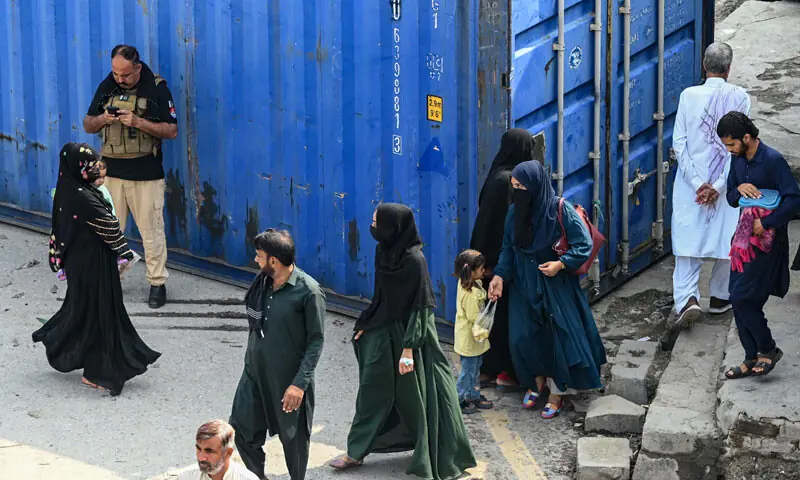 People walk past a shipping container along a blocked road in Peshawar as emergency was imposed in Khyber Pakhtunkhwa on Sunday. &mdash; Photo by Abdul Majeed Goraya