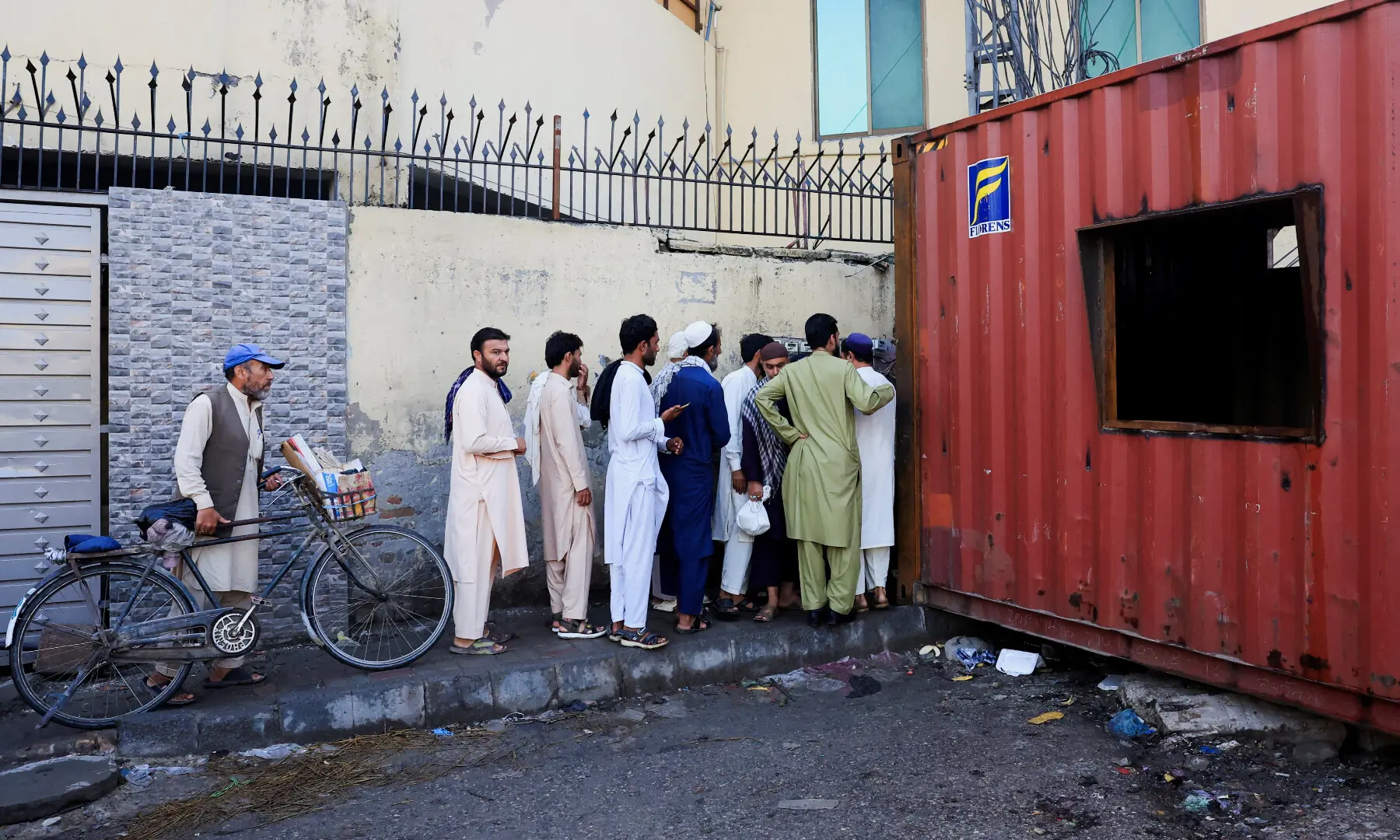 People cross shipping containers used to block access to the Red Zone, a day after Pakistan imposed a state of emergency in Khyber Pakhtunkhwa province, effectively suspending the provincial government run the PTI, in Peshawar, Pakistan, October 12, 2026. &mdash; Reuters