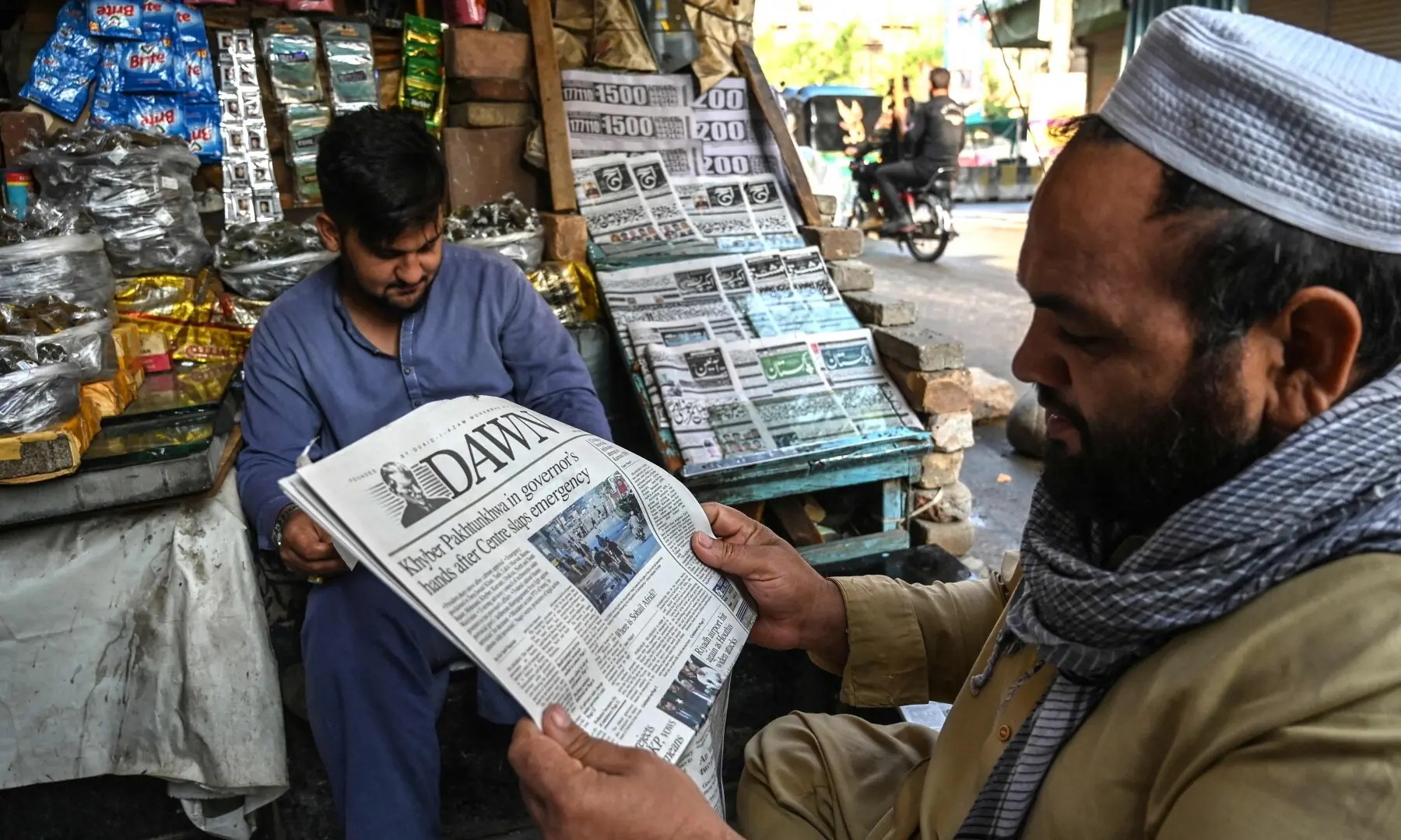 People read newspapers at a roadside stall after the  imposition of emergency and governor&rsquo;s rule in KP on October 12, 2026. &mdash;Reuters