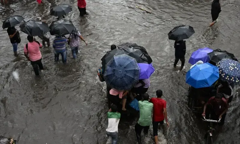 Commuters wade across a waterlogged street after heavy monsoon rains in India's Kolkata on September 23. — AFP Commuters wade across a waterlogged street after heavy monsoon rains in India's Kolkata on September 23. — AFP