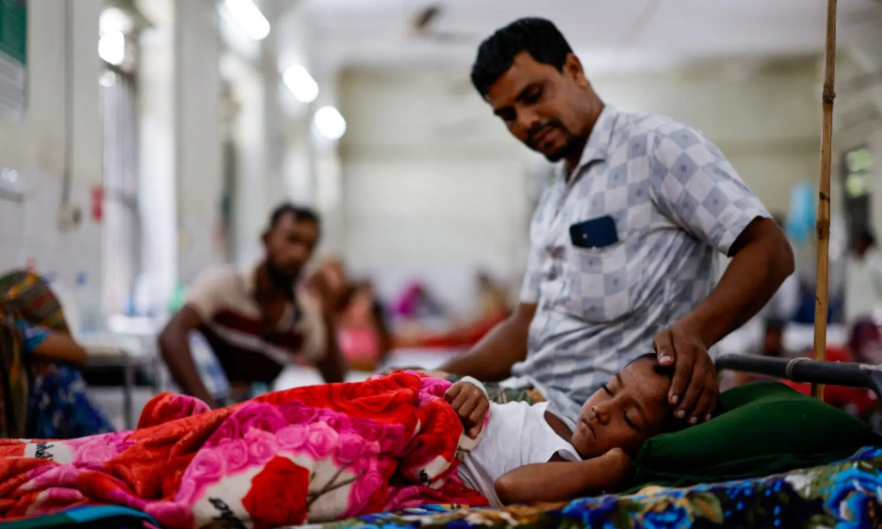 Mohammad Nasir Ali, 40, strokes the forehead of his seven-year-old son, Adil Ahmed, who has been admitted to the overcrowded measles isolation ward of Shahid Shamsuddin Ahmed Hospital for treatment, in Sylhet, Bangladesh, September 12, 2026. —Reuters