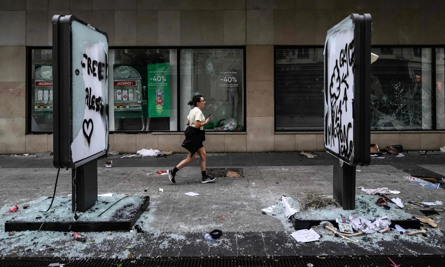  A pedestrian runs past damages and broken frontage windows of a shop a day after riot and looting following a nationwide protest against the &ldquo;high cost of living&rdquo;, in Lyon central-eastern France on Oct 18, 2026. &mdash; AFP 