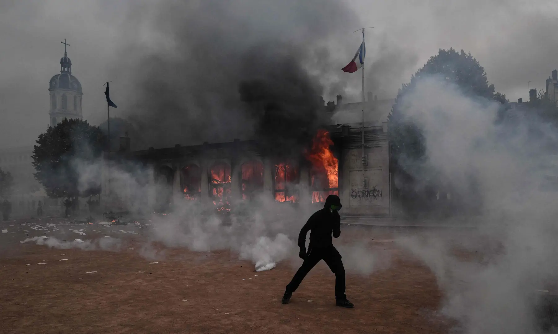  A protester kicks stands amid tear gas in front of Lyon&rsquo;s tourism office during a demonstration to protest against the &ldquo;high cost of living&rdquo;, in Lyon, southeastern France, on Oct 17, 2026. &mdash; AFP 