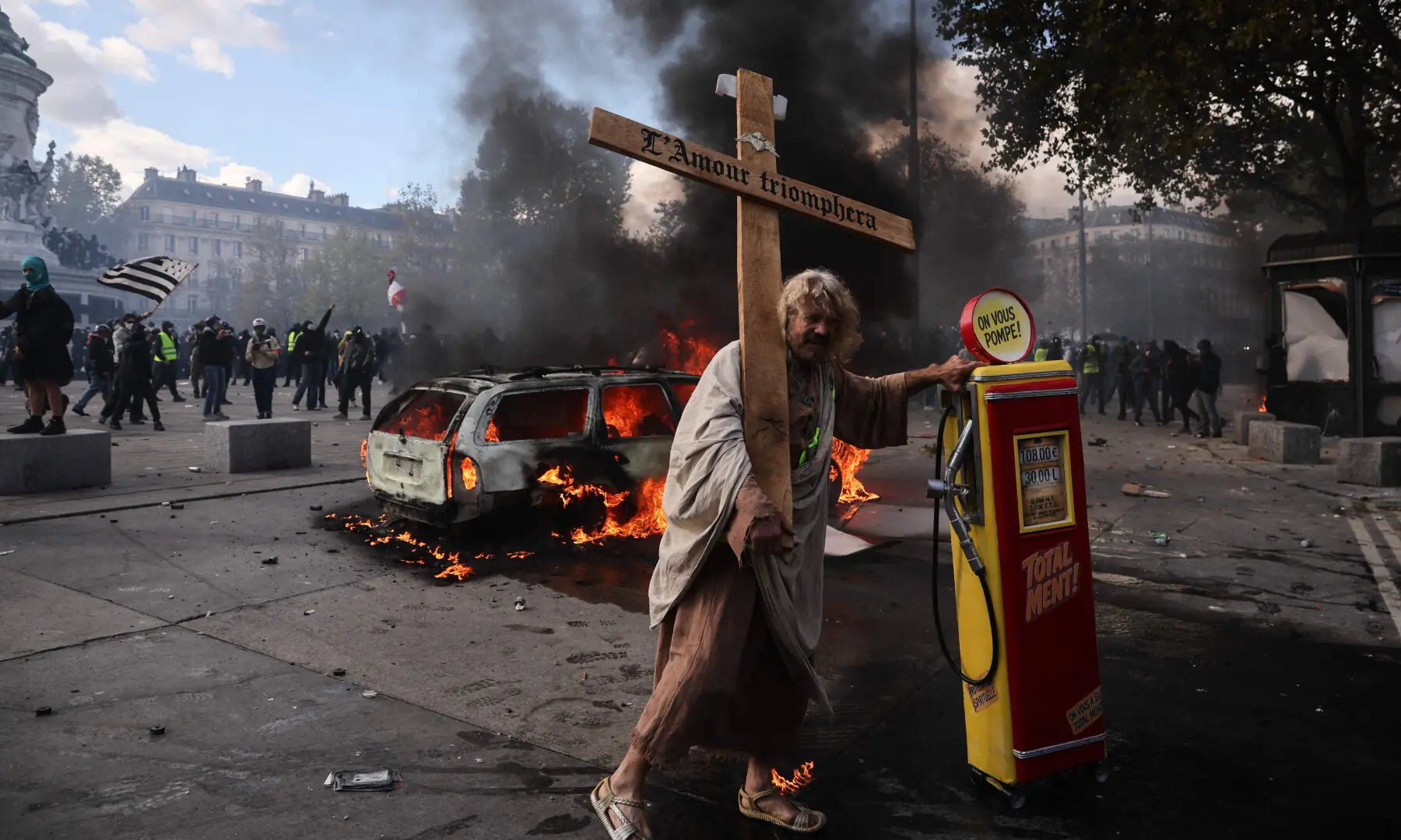  A protester holds a cross with an inscription reading &ldquo;love will triumph&rdquo; and stands next to a gasoline pomp during a demonstration to protest against the &ldquo;high cost of living&rdquo;, at Place de la Republique in Paris on Oct 17, 2026. &mdash; AFP 