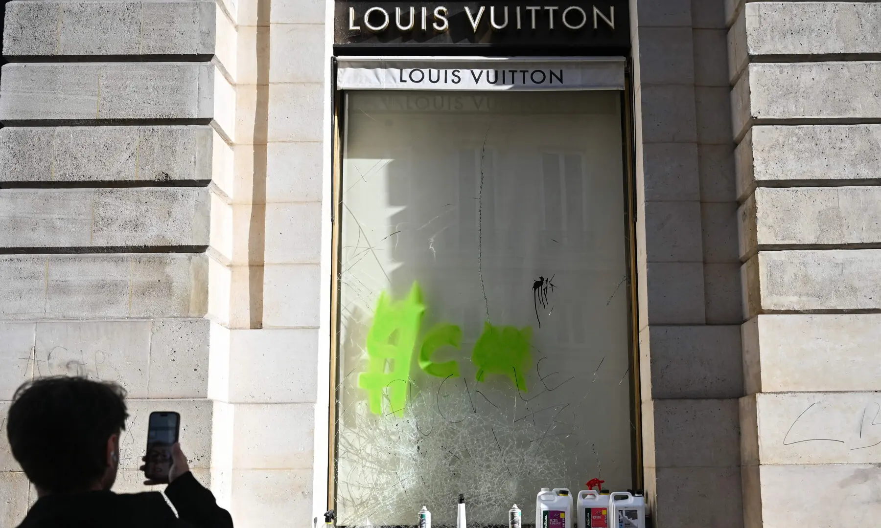  A pedestrian takes pictures of the damaged &ldquo;Louis Vuitton&rdquo; shop, in central Paris on Oct 18, 2026, a day after nationwide protests against the &ldquo;high cost of living&rdquo;. &mdash; AFP 