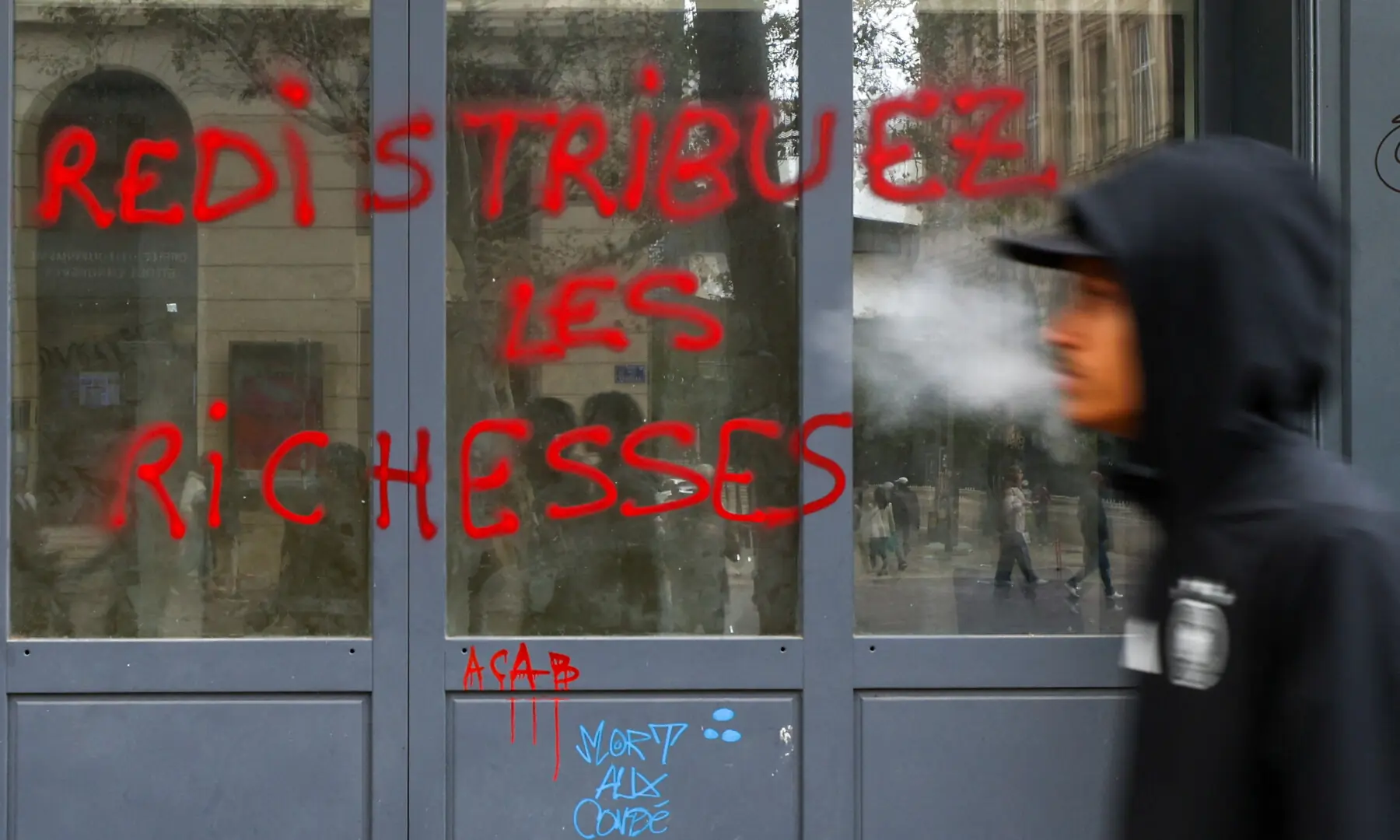  A man walks next to graffiti, which says &ldquo;Redistribute wealth&rdquo;, on a shop window, the day after clashes during a national day of demonstrations against the cost of living and rising fuel prices, in Marseille, France, on Oct 18, 2026. &mdash; Reuters 