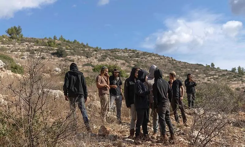 Israeli settlers gather as Palestinians harvest their olive trees in the Israeli-occupied West Bank village of Deir Abu Mashal on October 19, 2026. &mdash; AFP