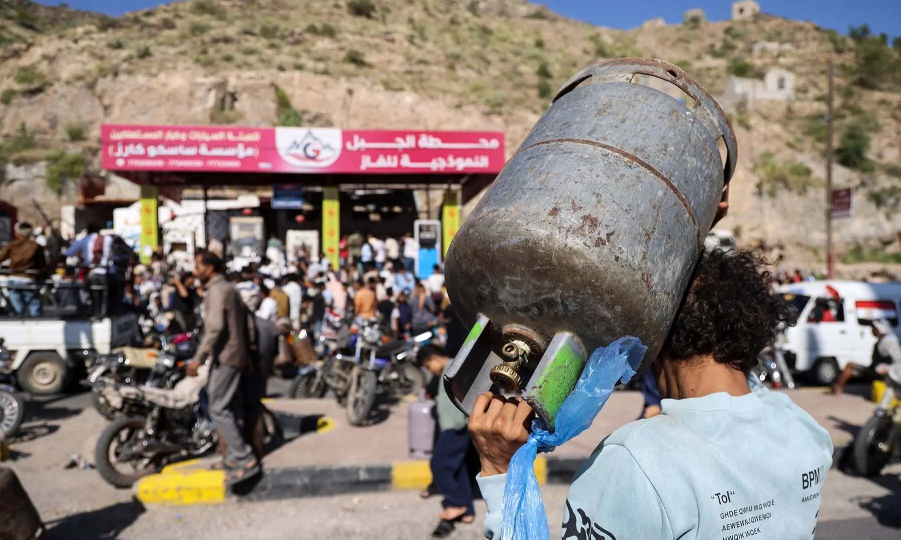 A Yemeni man carries a gas bottle as he waits with others to refill it at a refilling station in Taiz on October 19, 2026. &mdash; AFP