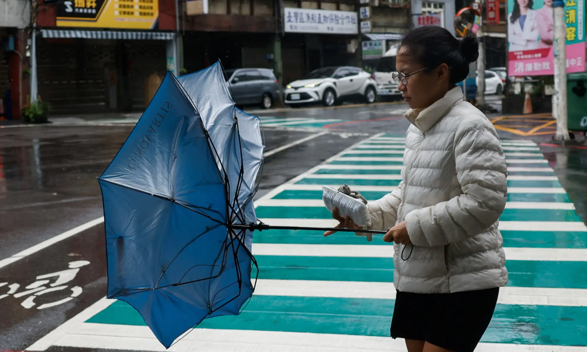 A pedestrian holds an umbrella in strong winds as Typhoon Champi approaches Taiwan, in Keelung, Taiwan on October 23, 2026. &mdash;Reuters