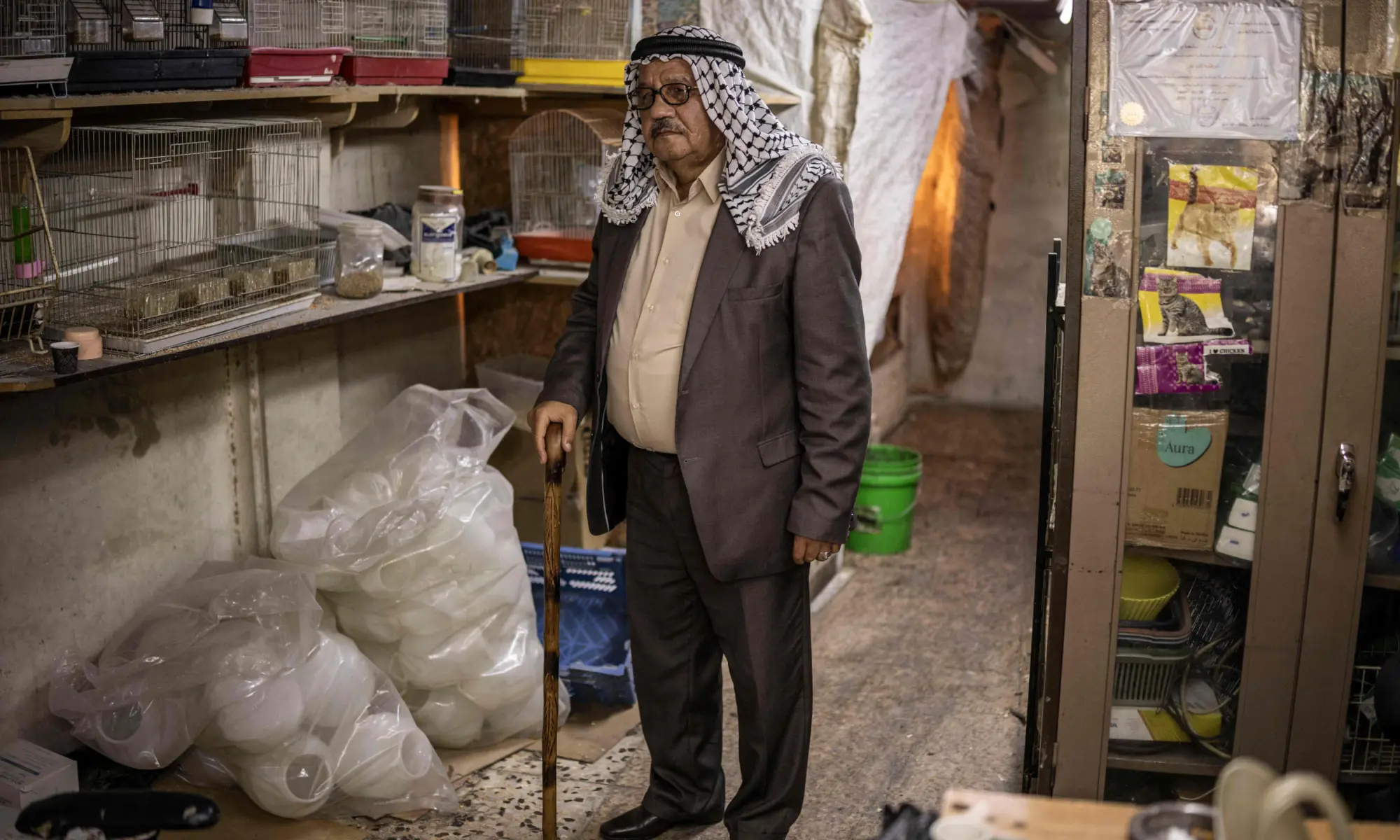 Higazi Shawer Al Tamimi, 70, who was evicted alongside his family from Ein Deir Baha neighbourhood by Israeli forces, poses for a picture inside his chicken and animal feed shop in Hebron, in the occupied West Bank on Oct 24, 2026. &mdash; AFP