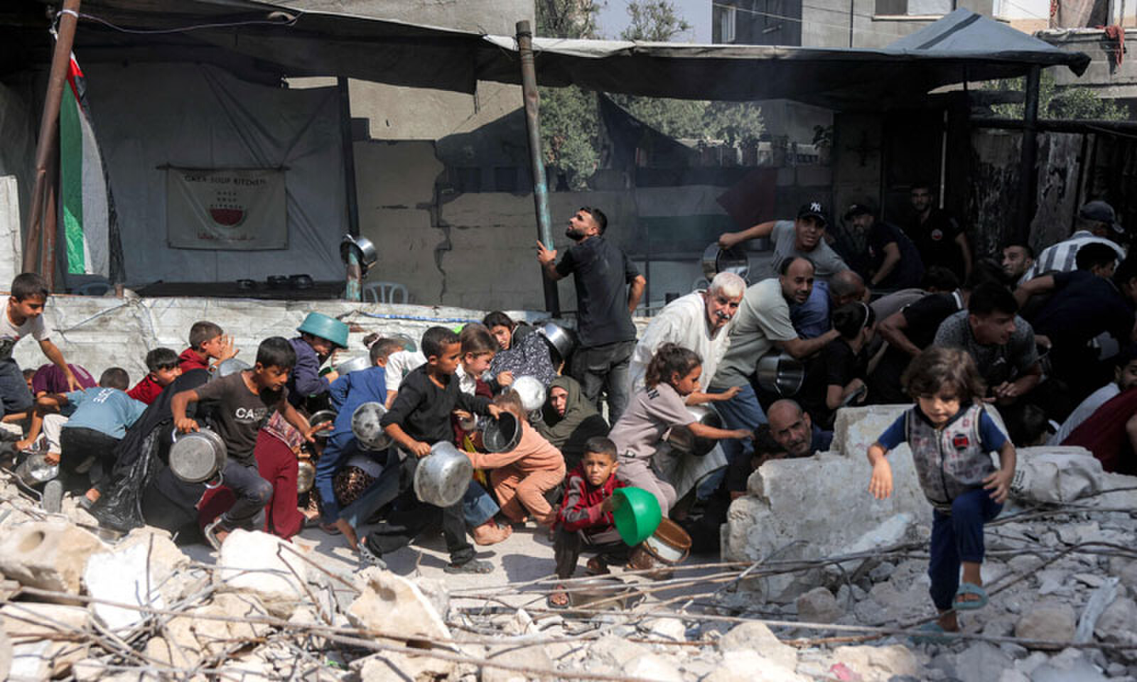 People scramble for cover amid a drone strike while they were queueing to receive meals from a charity kitchen in the Jabalia camp for Palestinian refugees in the northern Gaza Strip. —AFP People scramble for cover amid a drone strike while they were queueing to receive meals from a charity kitchen in the Jabalia camp for Palestinian refugees in the northern Gaza Strip. —AFP