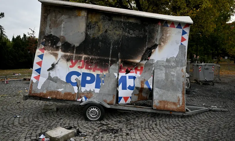 A burned election campaign banner of the Serbian Progressive Party (SNS) is pictured at a pro-government encampment in a park opposite the Serbian Parliament in Belgrade on Oct 26, 2026, after crowds celebrating election results entered the site the previous night and dismantled tents that had occupied the area for months, setting them alight along with a number of cars. — AFP