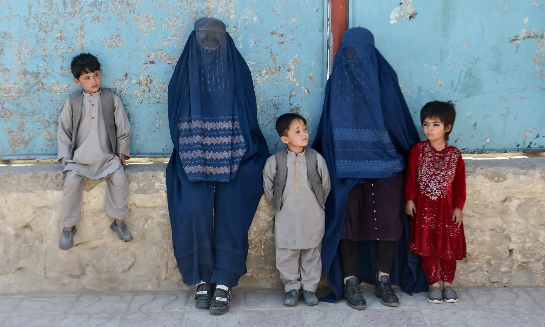 This photograph taken on October 20, 2026 shows burqa-clad women with their children standing along a street in Sheberghan in Afghanistan's Jawzjan province. — AFP This photograph taken on October 20, 2026 shows burqa-clad women with their children standing along a street in Sheberghan in Afghanistan's Jawzjan province. — AFP