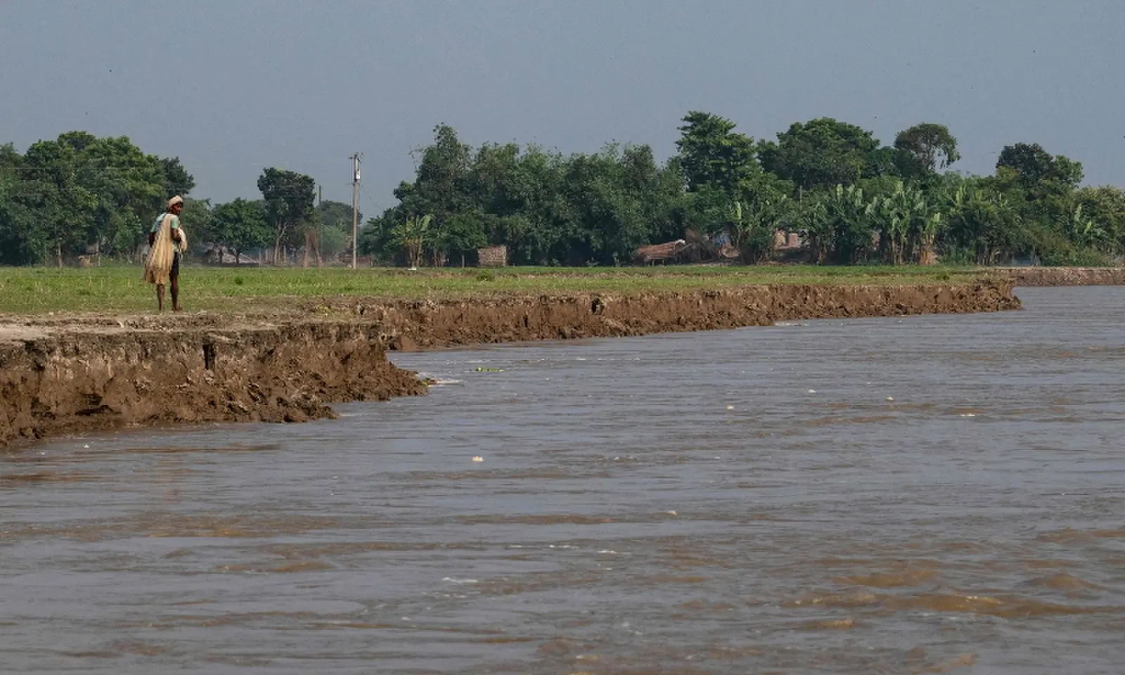 This photograph taken on October 12, 2026 shows a villager walking along the eroded Padma river embankment at Namo Jagannathpur village, near the Bangladesh-India frontier in Bangladesh's Rajshahi division. &mdash;AFP/File