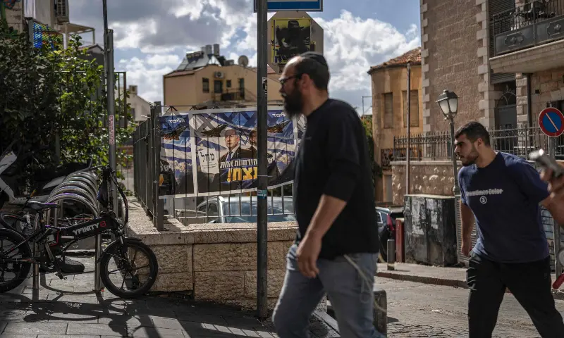 Israelis walk past a poster of Israel's Prime Minister Benjamin Netanyahu in Jerusalem on October 29, 2026, as Israelis await the final results of the general election. &mdash; AFP