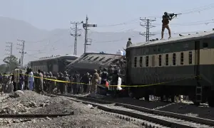 A soldier aims his weapon from atop a carriage as security officials inspect derailed train carriages after an explosion targeted a train in Quetta on May 24, 2026. โ AFP