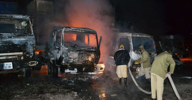 فائر بریگیڈ کے اہلکار نیٹو کنٹینرز میں لگی آگ کو بجھا رہے ہیں ۔ — فوٹو اے ایف پی