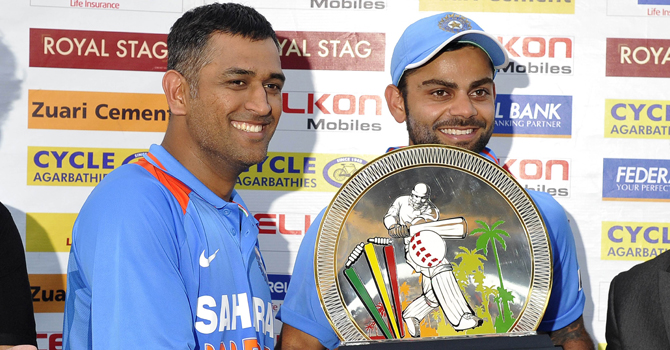 ہندوستانی کپتان مہندرا سنگھ دھونی اور ویرات کوہلی ٹرافی کے ہمراہ -- اے ایف پی فوٹو