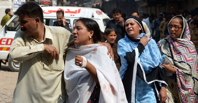 چرچ کے احاطے میں ہوئے دو خودکش حملوں کے بعد ایک زخمی خاتون کو ہسپتال منتقل کیا جارہا ہے—اے ایف پی فوٹو